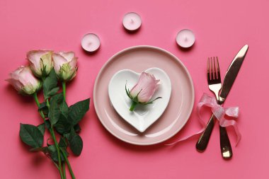 Sevgililer Günü için masa ayarı pembe arka planda güller ve mumlarla