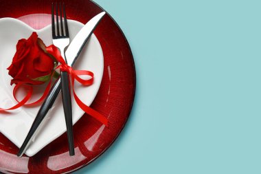 Mavi arka planda kırmızı gül olan Sevgililer Günü için masa ayarları, yakın plan