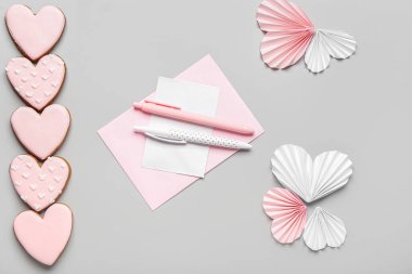 Tatlı kurabiyeler, mektup ve gri arka planda kağıt kalpler. Sevgililer Günü kutlaması