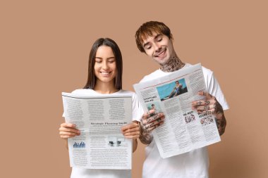 Bej arka planda gazeteleri olan genç bir çift