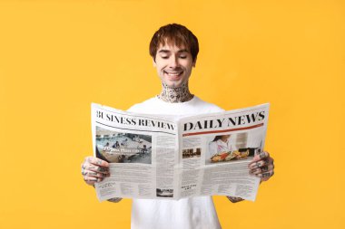 Sarı arka planda gazetesi olan yakışıklı bir genç.