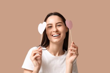 Bej arka planda kağıt kalpli güzel bir genç kadın.