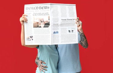 Kırmızı arka planda gazetesi olan çift.