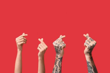 Kadın ve erkek, kırmızı arka planda parmaklarıyla kalp yapıyor.