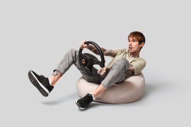 Gri arka planda direksiyonu olan yakışıklı genç adam.