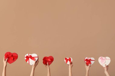 Kahverengi arka planda hediye kutuları olan kadınlar. Sevgililer Günü kutlaması