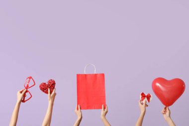 Hediyesi olan kadınlar, alışveriş çantası ve eflatun arkaplanlı dekor. Sevgililer Günü kutlaması