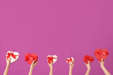 Mor arka planda kalp şeklinde hediye kutuları olan kadınlar. Sevgililer Günü kutlaması