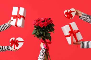 Hediye kutularını tutan kadın eller ve kırmızı arka planda güzel güller. Sevgililer Günü kutlaması