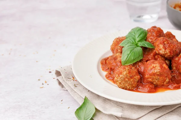 Plate of tasty meat balls with sauce on light background