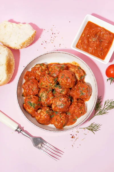 Bowl of tasty meat balls with sauce on pink background