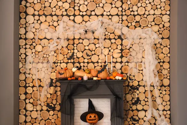 Fireplace with Halloween pumpkins and decorations near wooden wall