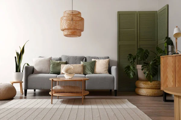 stock image Interior of modern living room with grey sofa, green folding screen and coffee table