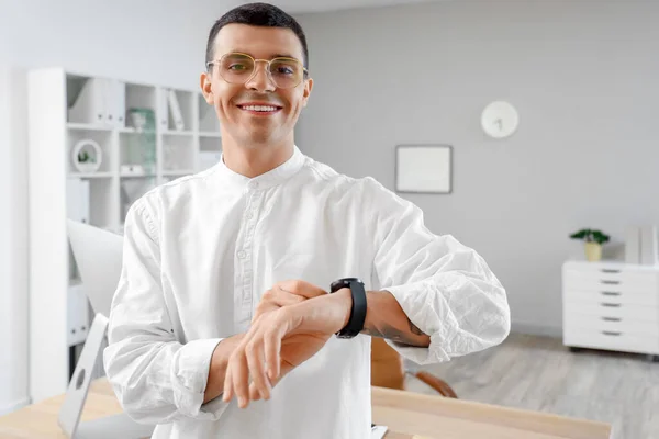 Handsome young man with looking at watch in office