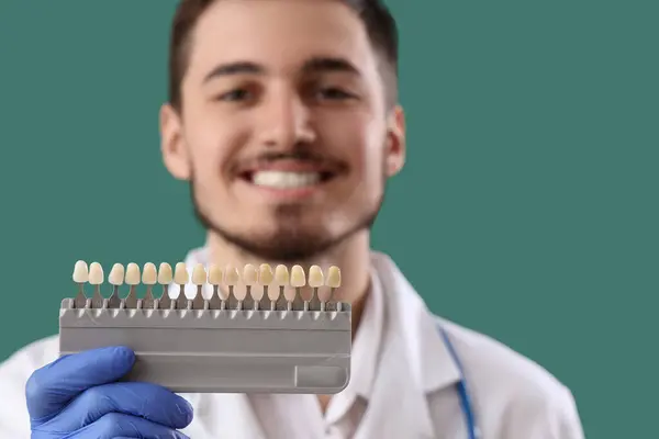 Junge Männliche Zahnarzt Mit Zähnen Farbproben Auf Grünem Hintergrund Zahnpflegekonzept — Stockfoto