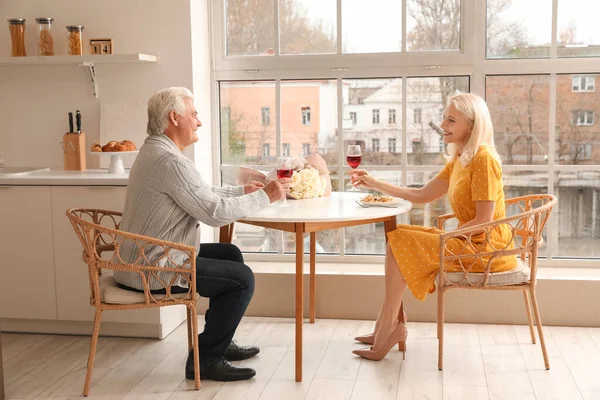 Mature couple drinking wine at dining table in kitchen