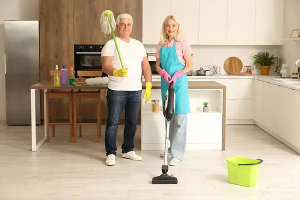 Mature couple with cleaning supplies in kitchen