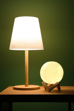 Karanlık odadaki ahşap masada farklı parlayan lambalar.