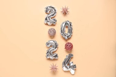 Şekil 2024 balonlardan, Noel süslemelerinden ve turuncu arka planda konfetilerden yapılmıştır.
