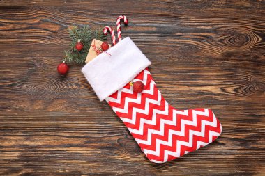 Noel çorabı, köknar dalları, toplar, hediye kutusu ve tahta arka planda şeker kamışı