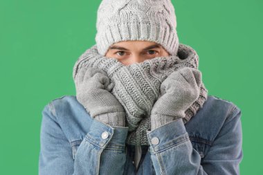 Yeşil arka planda, kışlık elbiseli yakışıklı adam, yakın plan.