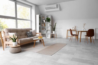 Konforlu kanepe ve beyaz mobilyalarla aydınlık oturma odasının içinde.