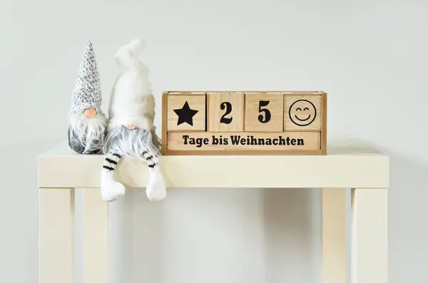 Wooden countdown calendar with toys on table near light wall