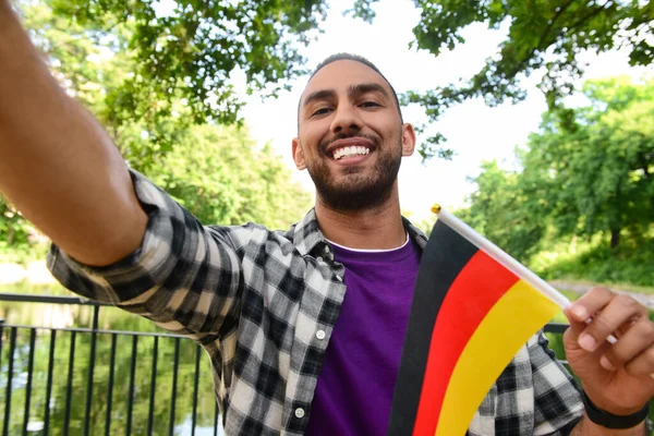 Young man with flag of Germany taking selfie in park, closeup