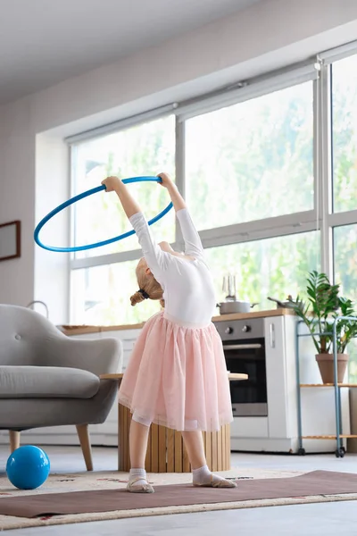 Cute little girl doing gymnastics with hula hoop at home