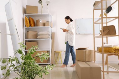 Tablet bilgisayarı olan Asyalı kadın satıcı depoda çalışıyor.