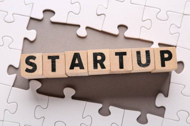 Sözcükler STARTUP ve gri arkaplanda yapboz parçaları