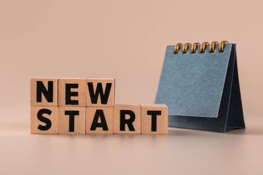 Yeni Başlat metnini içeren küpler ve bej arkaplan üzerinde boş çevirme takvimi