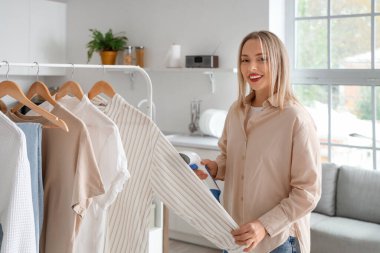 Güzel, genç bir kadın. Buharlı giysileri modern buharlı evde.