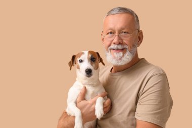 Orta yaşlı bir adam ve bej arka planda sevimli bir köpek.