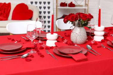 Sevgililer Günü için hazırlanmış şölen masası kırmızı güller ve evde yanan mumlarla süslenmiş.