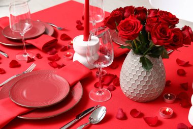 Sevgililer Günü kutlaması için yemek masası, mumlar ve kırmızı güller.