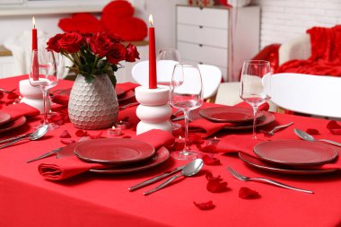 Sevgililer Günü için hazırlanmış şölen masası kırmızı güller ve evde yanan mumlarla süslenmiş.