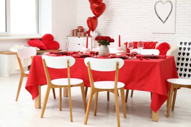 Sevgililer Günü için hazırlanmış şölen masası kırmızı güller ve evde yanan mumlarla süslenmiş.