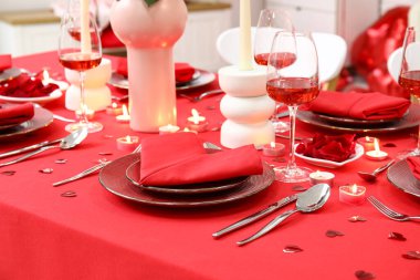 Sevgililer Günü kutlaması için yemek masası, mumlar ve kağıt kalpler.