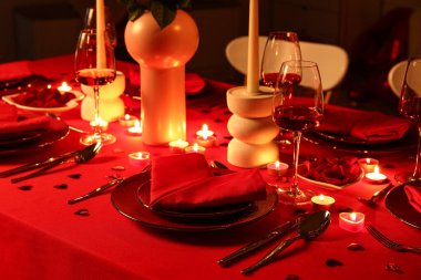 Akşamki Sevgililer Günü kutlaması için yemek masası, yanan mumlar ve dekor.