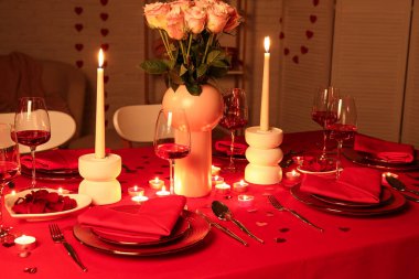 Akşamki Sevgililer Günü kutlaması için yemek masası, yanan mumlar ve pembe güller.