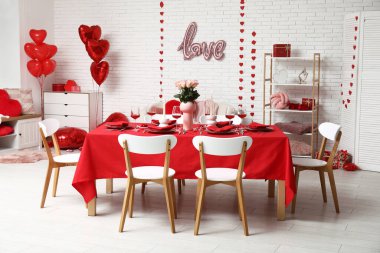 Sevgililer Günü için evde pembe güller ve mumlarla süslenmiş masa.