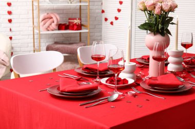 Sevgililer Günü için evde pembe güller ve mumlarla süslenmiş masa.