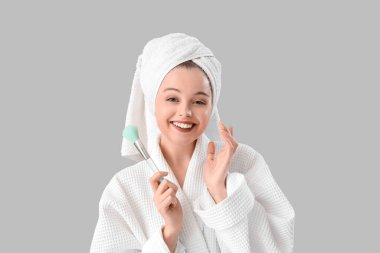 Bornozlu ve makyajlı genç bir kadın. Arka planda duş aldıktan sonra, yakın plan.