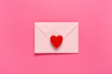 Zarflı kompozisyon ve pembe arka planda kırmızı kalp. Sevgililer Günü kutlaması