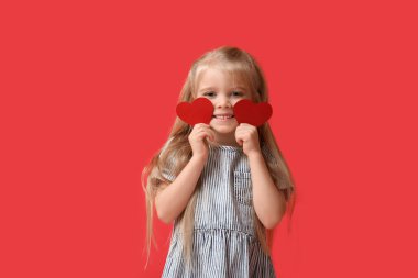 Kırmızı arka planda kağıt kalpli şirin küçük bir kız. Sevgililer Günü kutlaması