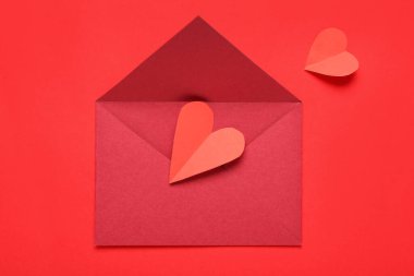 Zarflı kompozisyon ve kırmızı arka planda kağıt kalpler. Sevgililer Günü kutlaması