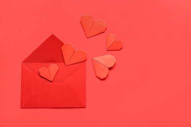 Zarflı kompozisyon ve kırmızı arka planda kağıt kalpler. Sevgililer Günü kutlaması