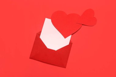 Kırmızı arka planda zarf, kart ve kağıt kalpli kompozisyon. Sevgililer Günü kutlaması