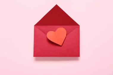Zarflı kompozisyon ve pembe arka planda kırmızı kağıt kalp. Sevgililer Günü kutlaması